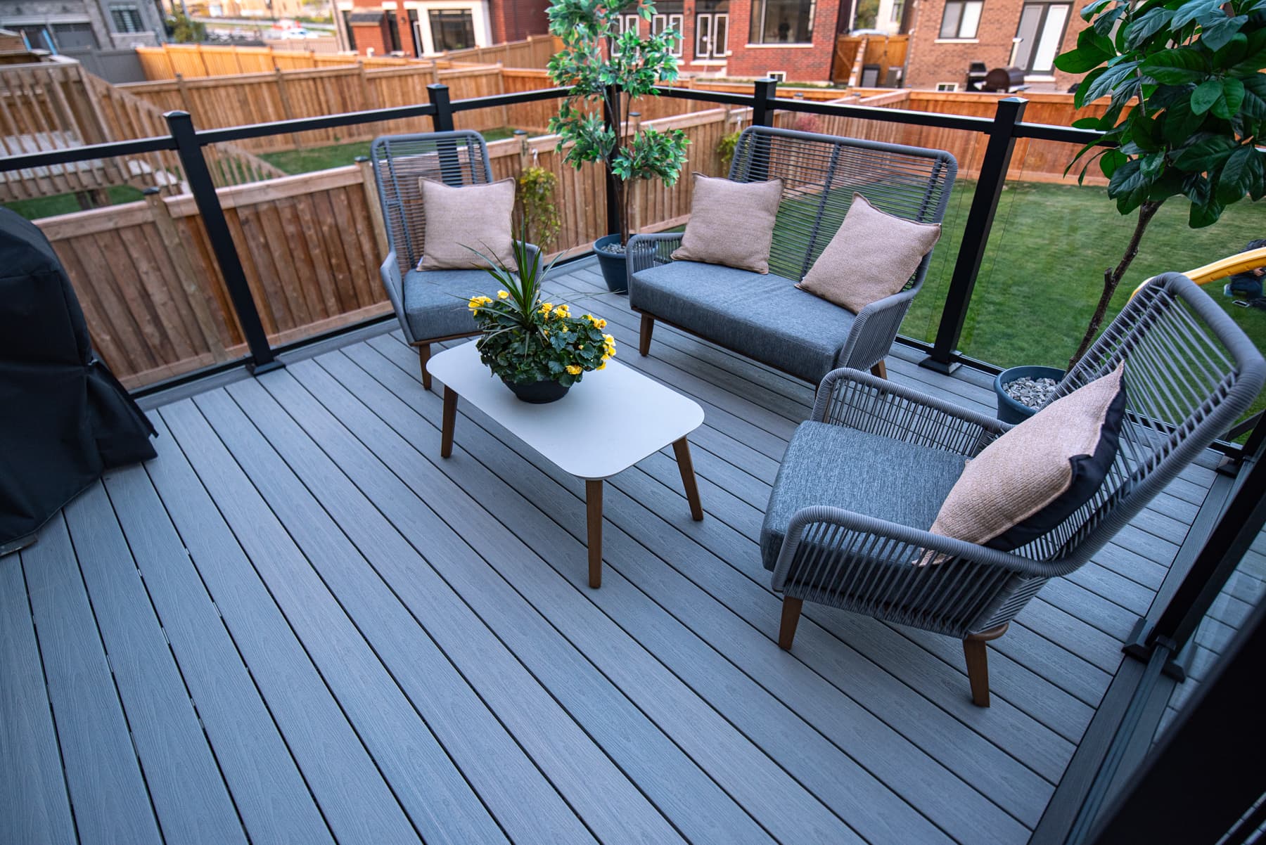 Grey composite deck with glass railing and outdoor lounge furniture