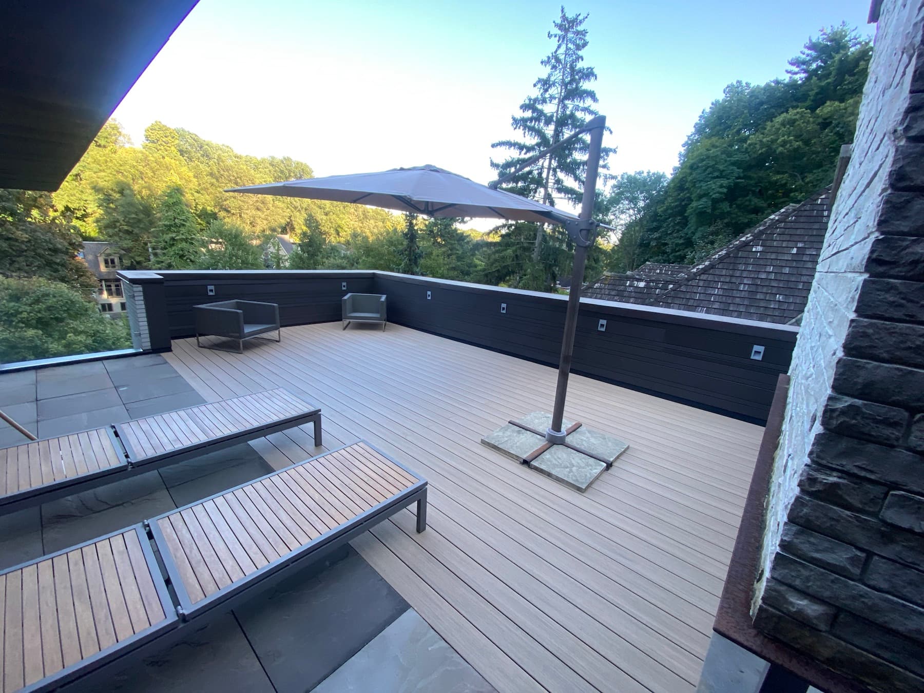Rooftop composite deck with privacy wall surrounded by trees