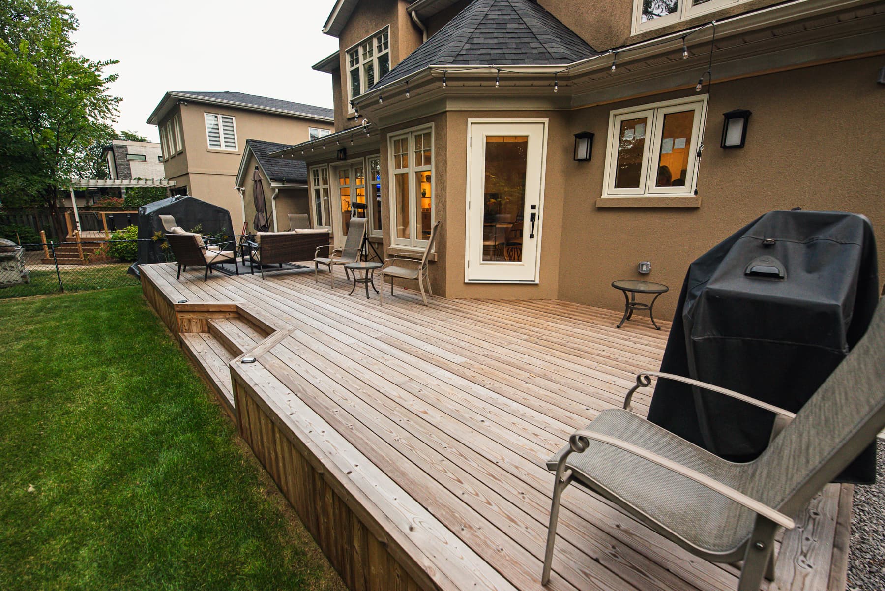 Pressure-treated wood backyard deck beside a home with outdoor furniture