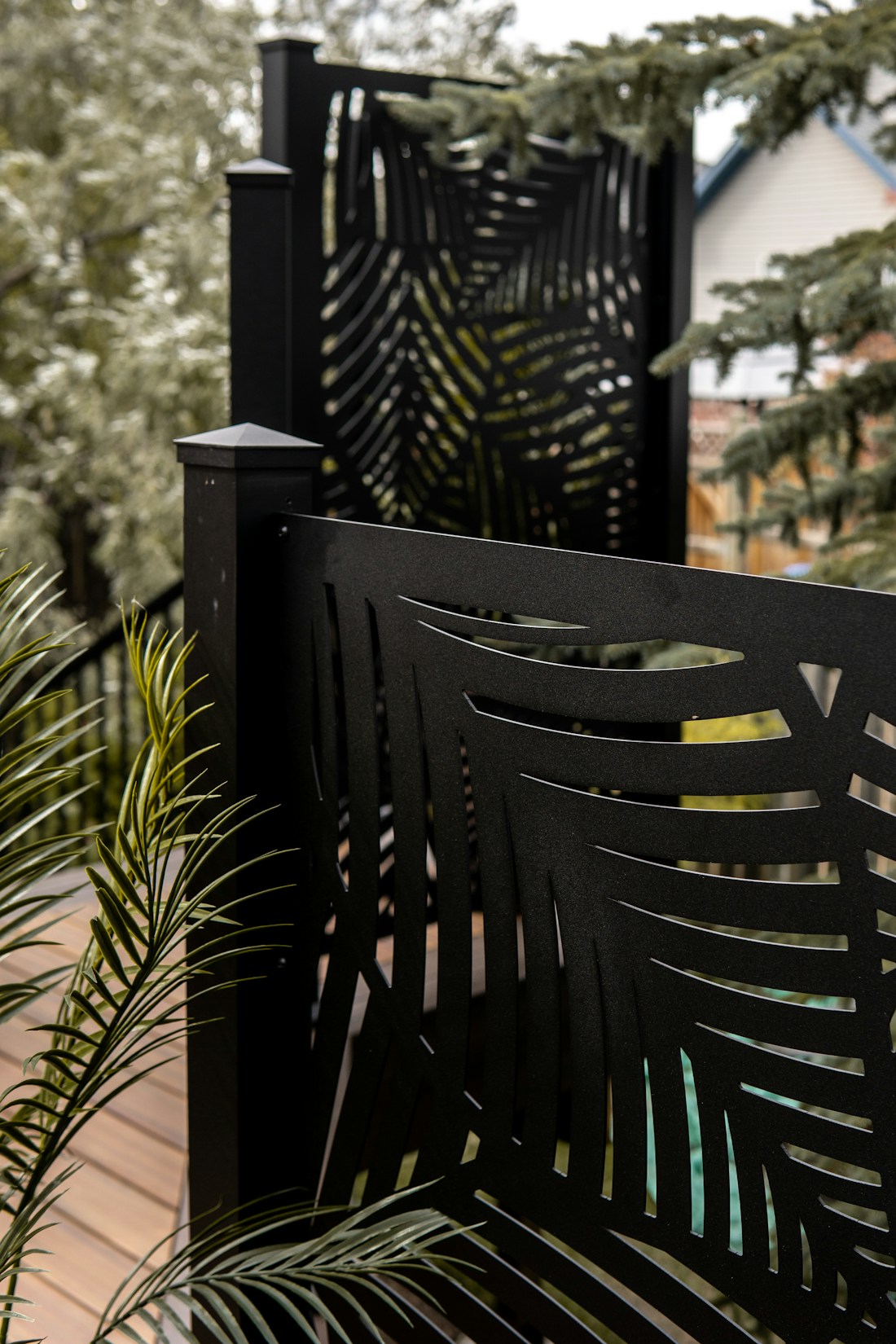 Black decorative privacy screens with plants beside a backyard deck